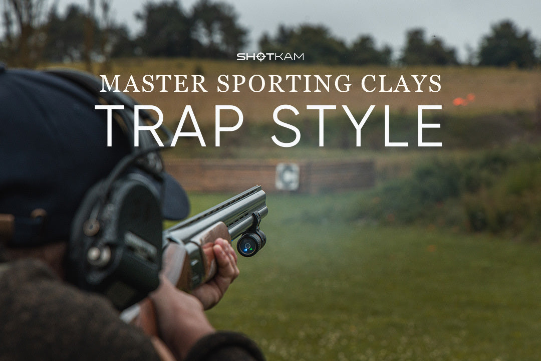 Trap shooter tracking a clay pigeon using ShotKam on barrel at open field range.
