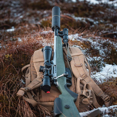 ShotKam Gen 4 mounted on a rifle with the Moderator Mount, resting on a hunting pack in a snowy Canadian landscape. Ideal for stalking, long-range shooting, and recording hunts.