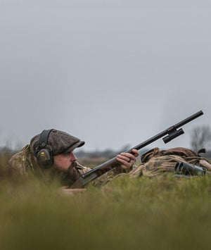 Hunter in camouflage gear with a rifle in a grassy field in Canada with ShotKam