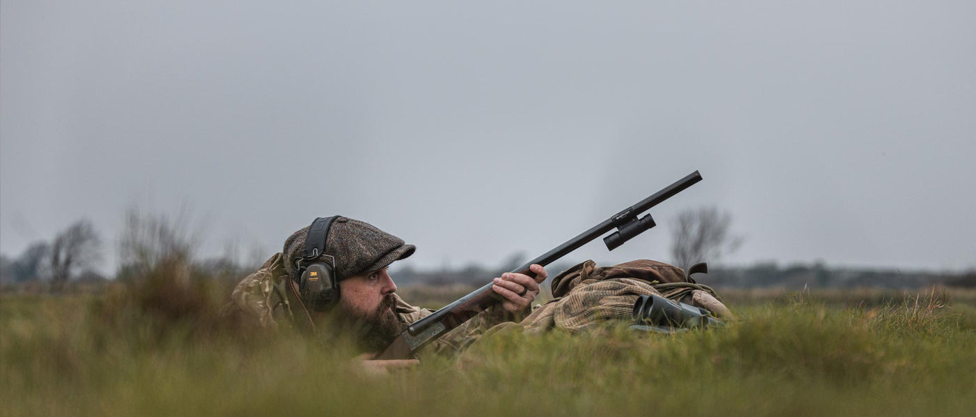 Person in camouflage gear with a rifle in a grassy field with ShotKam